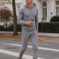 Ein Mann läuft in einem Kaschmir Hoodie und Hose in Grau über die Straße [ai-mod-b]