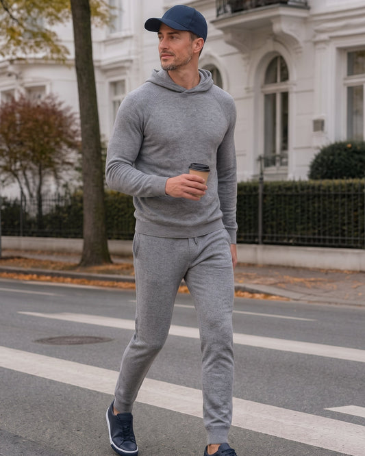 Ein Mann läuft in einem Kaschmir Hoodie und Hose in Grau über die Straße