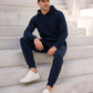 Ein Mann sitzt auf den Stufen in einem Kaschmir Hoodie und Kaschmir Hose in Marineblau