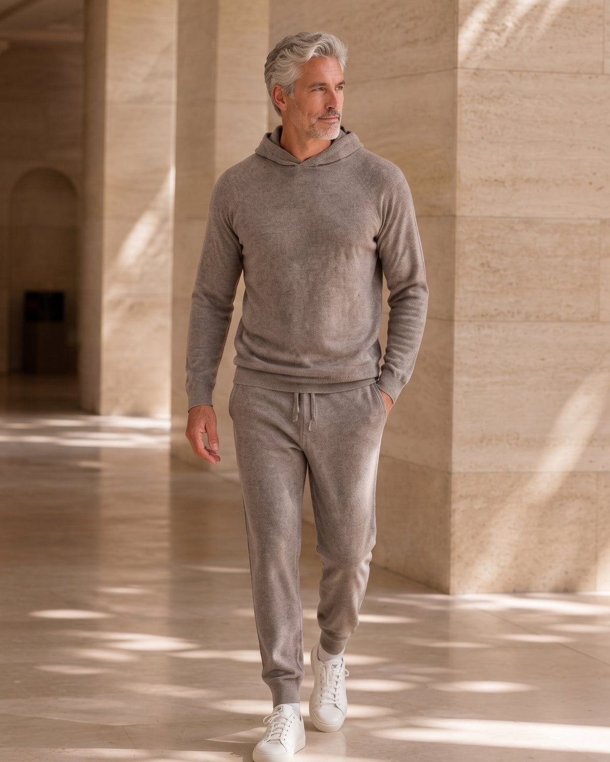 Ein Mann in einem Kaschmir Hoodie und Hose in Farbe Taupe